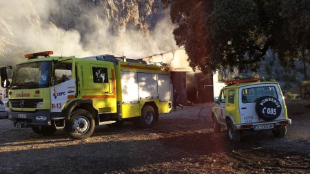 Vehículos de bomberos ante el pajar incendiado.