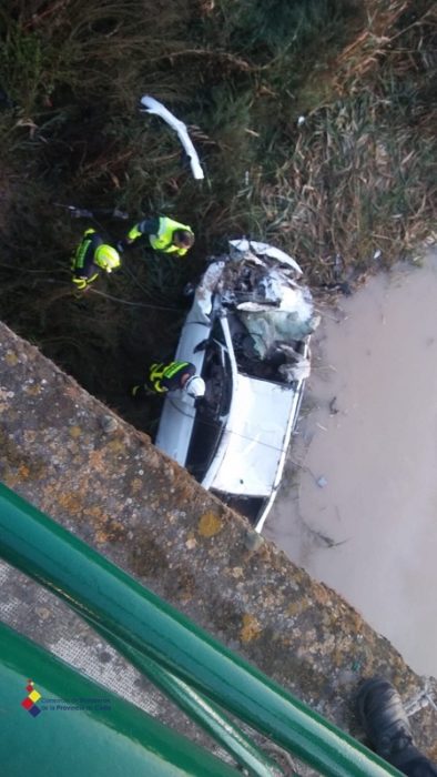 Vehículo accidentado y bomberos en la operación de rescate del cadáver.