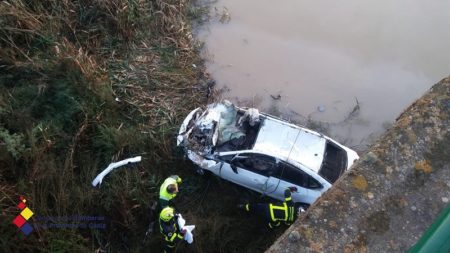 Vehículo accidentado y bomberos en la operación de rescate del cadáver.